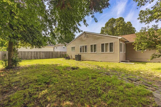 rear view of house featuring a lawn and central AC