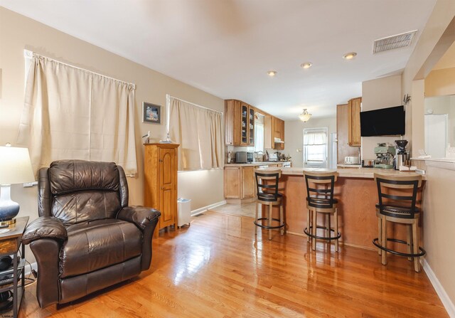 kitchen with light wood-type flooring, kitchen peninsula, and a breakfast bar area