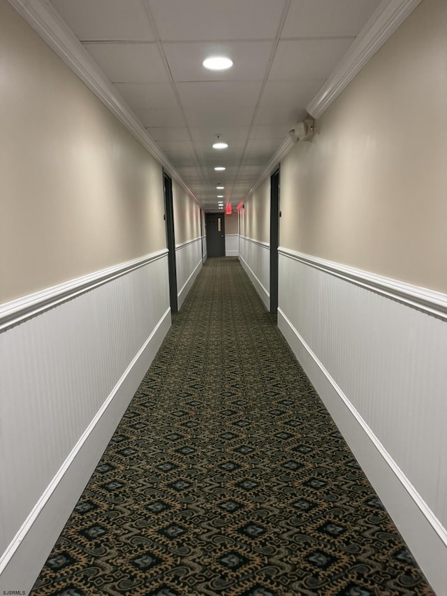 hallway with ornamental molding and dark colored carpet