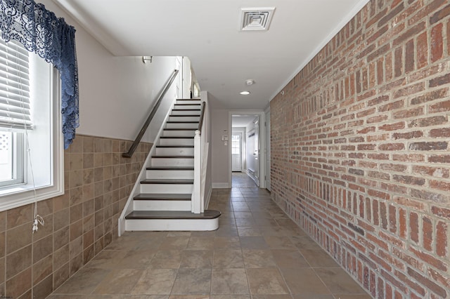 staircase with brick wall and plenty of natural light