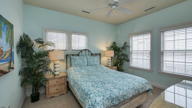 carpeted bedroom with visible vents, multiple windows, baseboards, and ceiling fan