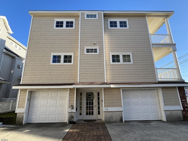 multi unit property with aphalt driveway, a balcony, and a garage