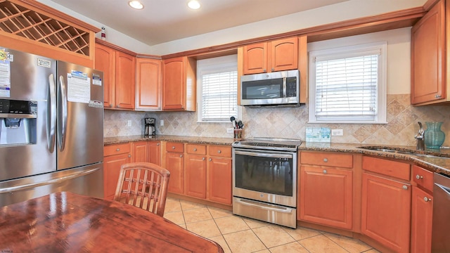 kitchen with light tile patterned flooring, appliances with stainless steel finishes, tasteful backsplash, and a sink