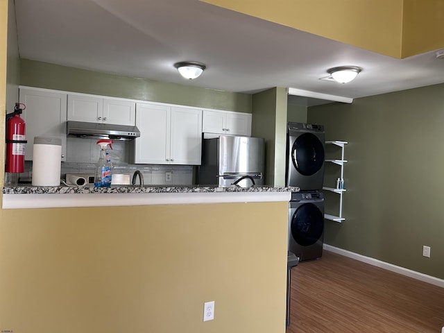 kitchen with white cabinetry, tasteful backsplash, stainless steel fridge, kitchen peninsula, and stacked washing maching and dryer