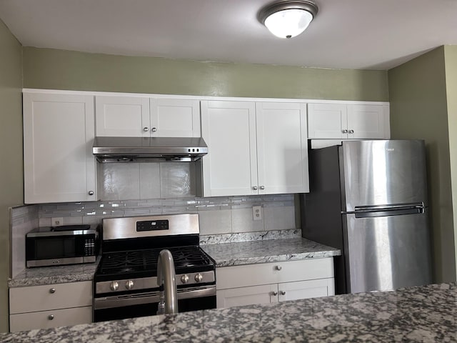 kitchen with backsplash, white cabinets, range hood, and stainless steel appliances