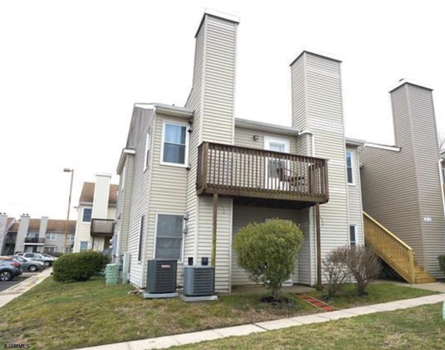 back of property featuring central AC unit and a yard