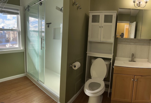 bathroom featuring toilet, hardwood / wood-style flooring, vanity, backsplash, and a shower with door