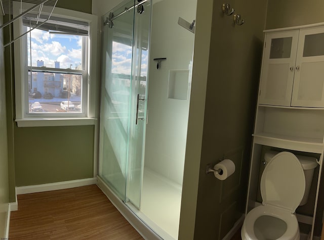 bathroom featuring toilet, an enclosed shower, and hardwood / wood-style flooring