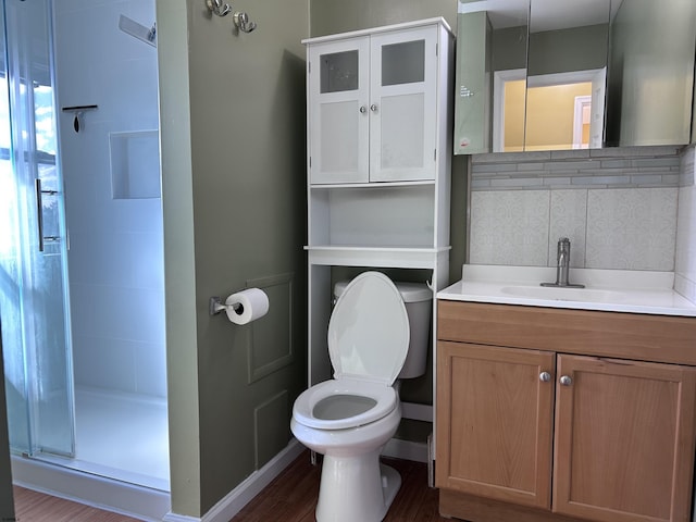 bathroom featuring wood-type flooring, a shower with door, toilet, vanity, and decorative backsplash