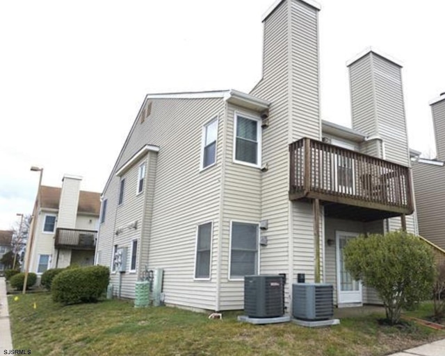 view of side of home with central AC unit and a lawn