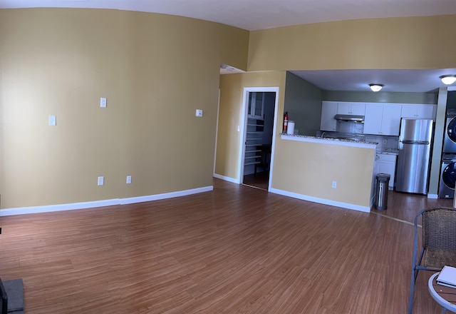 unfurnished living room featuring dark wood-type flooring and stacked washing maching and dryer