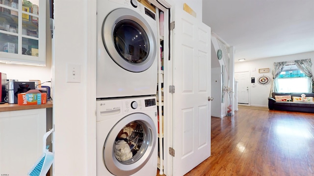 laundry room with stacked washer / dryer and wood-type flooring