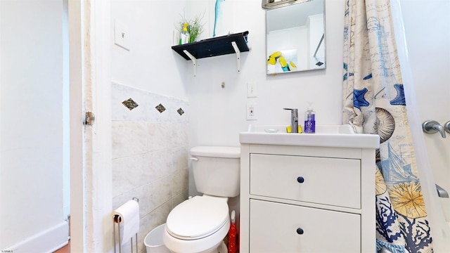 bathroom featuring vanity, tile walls, and toilet