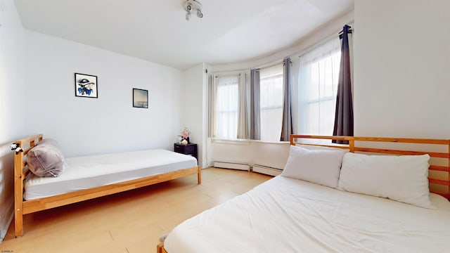 bedroom featuring baseboard heating and light hardwood / wood-style flooring