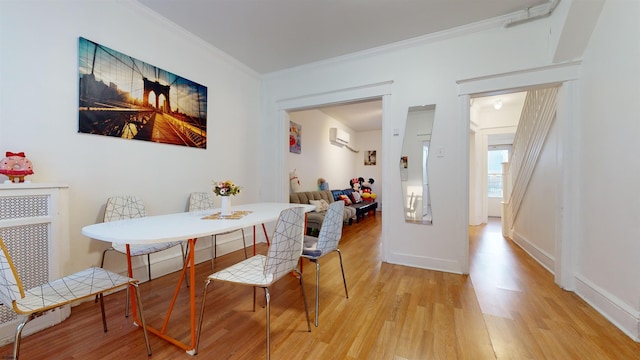 dining area with breakfast area, ornamental molding, a wall mounted AC, and light hardwood / wood-style floors