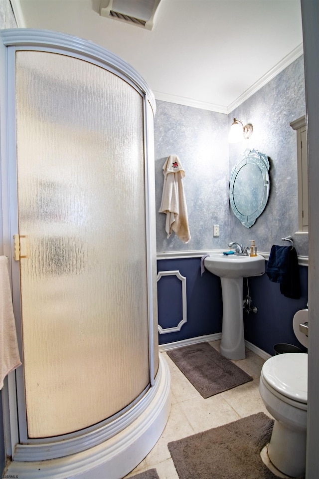 bathroom with tile patterned flooring, crown molding, toilet, and a shower with shower door