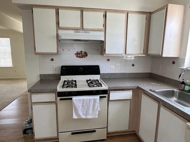 kitchen featuring sink, light hardwood / wood-style flooring, white cabinets, white gas range, and decorative backsplash