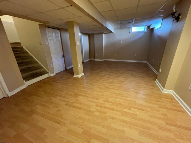 basement featuring a paneled ceiling and light wood-type flooring