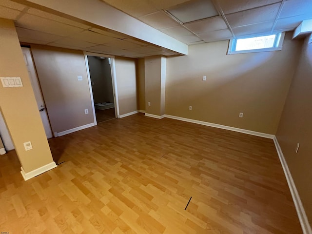 basement with hardwood / wood-style flooring and a paneled ceiling