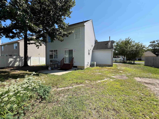 rear view of house with central AC and a lawn