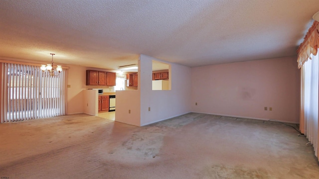 unfurnished living room featuring light colored carpet, a notable chandelier, and a textured ceiling