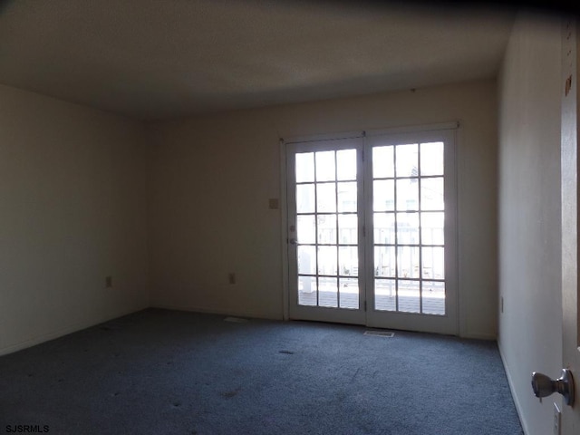 empty room featuring carpet, plenty of natural light, and visible vents