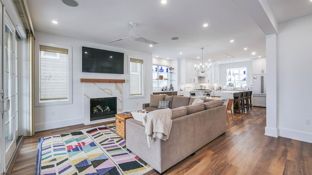 living room with a notable chandelier, dark wood-type flooring, and a premium fireplace