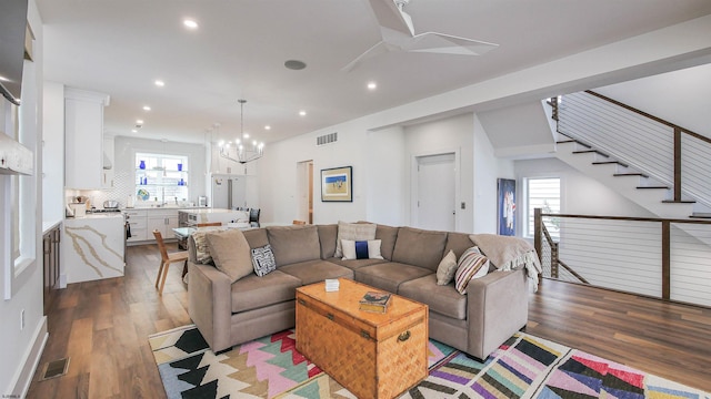 living room with ceiling fan with notable chandelier and light hardwood / wood-style floors