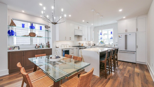 kitchen with high end appliances, white cabinetry, decorative light fixtures, and a center island