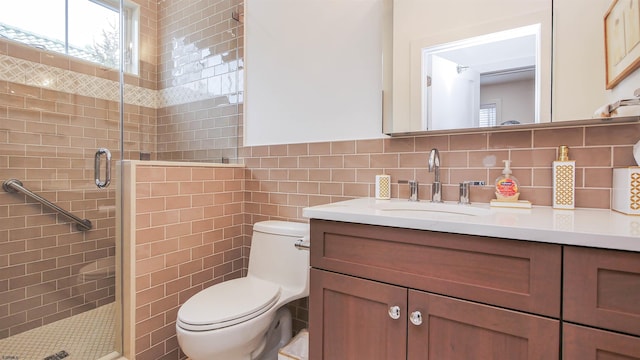 bathroom with a shower with door, vanity, tile walls, and toilet