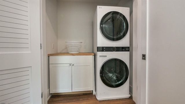 clothes washing area featuring cabinets, stacked washer / drying machine, and dark hardwood / wood-style flooring