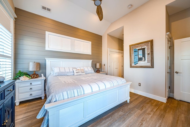 bedroom featuring multiple windows, vaulted ceiling, a closet, and wood-type flooring