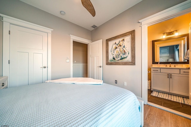 bedroom featuring ceiling fan, sink, ensuite bath, and light wood-type flooring