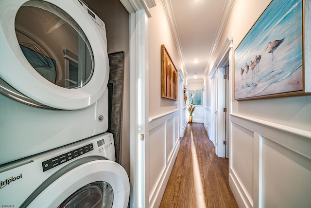 clothes washing area featuring crown molding, stacked washer / dryer, and dark wood-type flooring