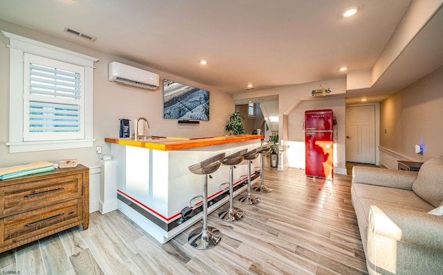 bar featuring butcher block countertops, sink, a wall mounted AC, and light wood-type flooring