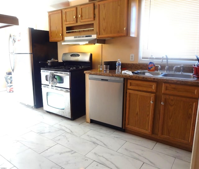 kitchen featuring stainless steel appliances, sink, and dark stone countertops