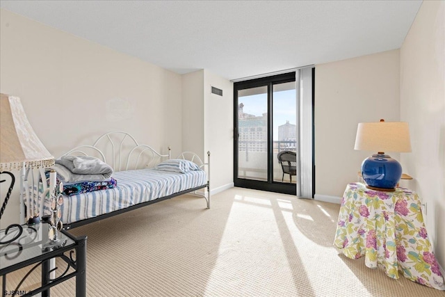 bedroom featuring carpet, access to exterior, and a wall of windows