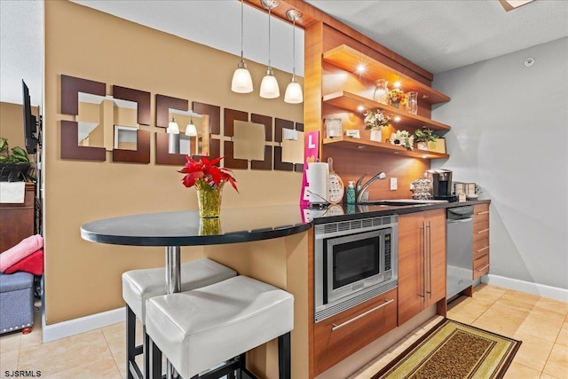 kitchen featuring stainless steel appliances, pendant lighting, a kitchen bar, and light tile patterned floors