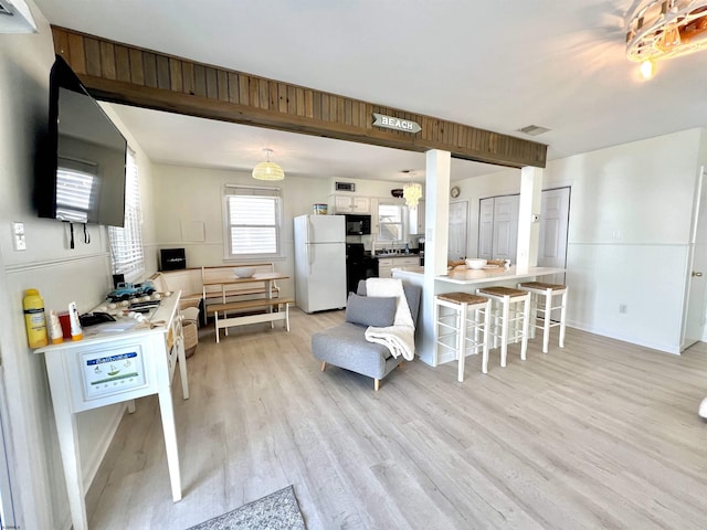 kitchen featuring pendant lighting, a breakfast bar area, white cabinets, white refrigerator, and light hardwood / wood-style floors