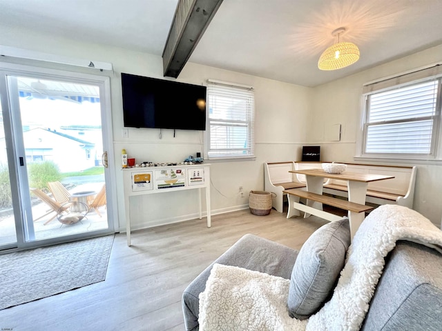 living room with a wealth of natural light, beamed ceiling, and light wood-type flooring