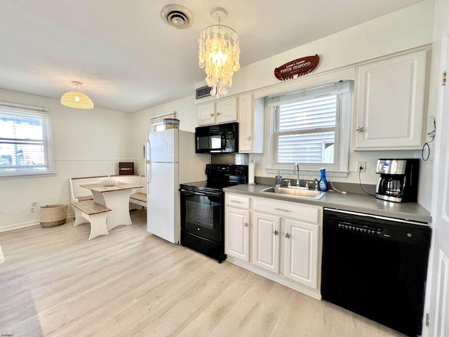 kitchen featuring decorative light fixtures, white cabinetry, sink, and black appliances