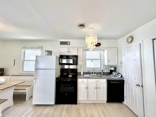 kitchen featuring sink, black appliances, hanging light fixtures, light hardwood / wood-style floors, and white cabinets