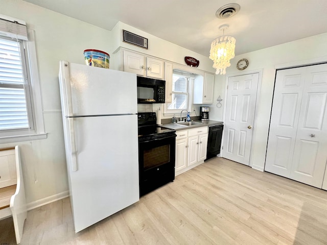 kitchen featuring hanging light fixtures, black appliances, and white cabinets