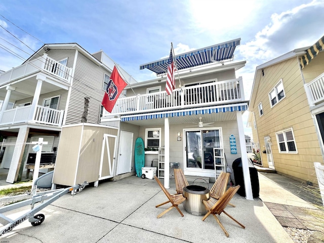 rear view of house with a patio area, a balcony, and an outdoor fire pit