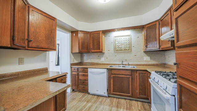 kitchen featuring sink, white appliances, backsplash, and light wood-type flooring