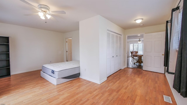 unfurnished bedroom featuring light wood-type flooring, ceiling fan, and a closet