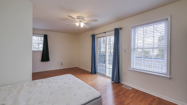 bedroom with wood-type flooring, access to outside, and ceiling fan