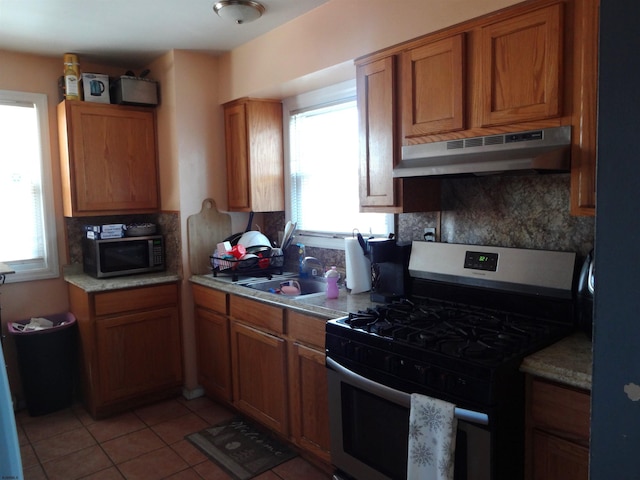 kitchen with light tile patterned flooring, stainless steel range with gas cooktop, sink, and decorative backsplash