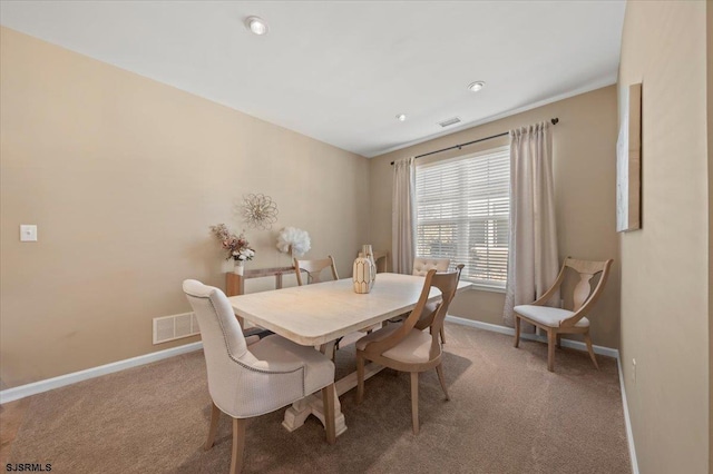 carpeted dining room with visible vents and baseboards