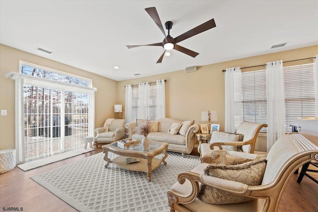 living area with ceiling fan, wood finished floors, and visible vents